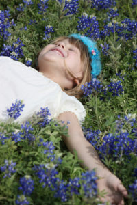 Child laying in a flower patch during mental health awareness month. 