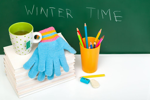 Winter gloves lay on school supplies.