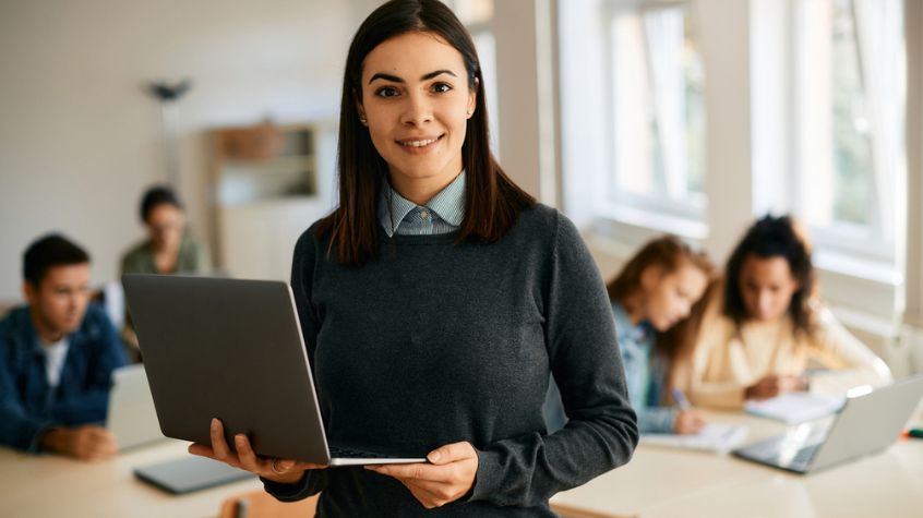 Teacher using a laptop to plan professional development hours and continuing education for license renewal.